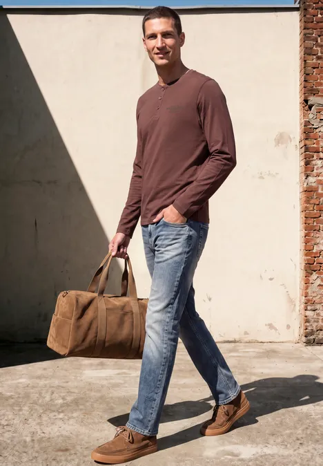 Angerautes Henleyshirt mit Printdetail maroon brown Ein Mann in braunem Shirt, Jeans und braunen Schuhen trägt eine Canvas-Tasche und geht lächelnd.
