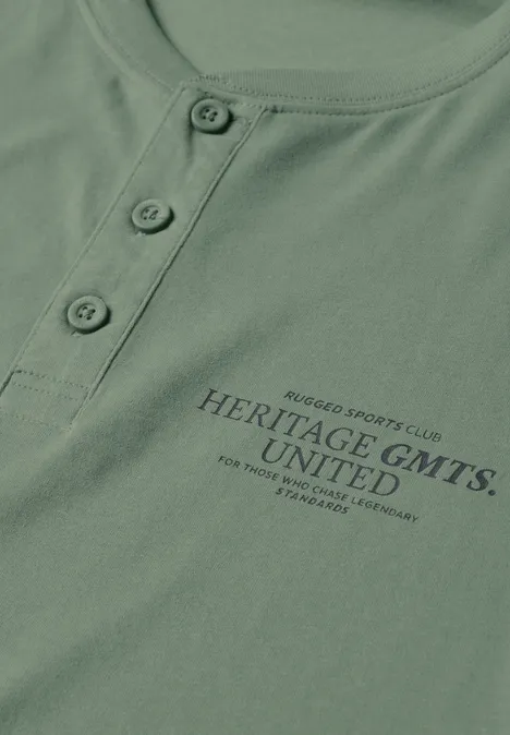 Angerautes Henleyshirt mit Printdetail willow green Grünes Shirt mit Knopfleiste und Aufdruck 'HERITAGE GMTS. UNITED'