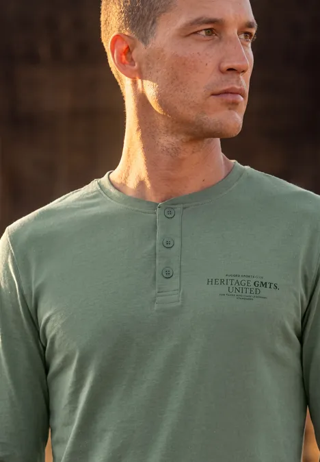 Angerautes Henleyshirt mit Printdetail willow green Ein junger Mann mit kurzem Haar trägt ein olivgrünes Langarmshirt mit Knopfleiste und Print.
