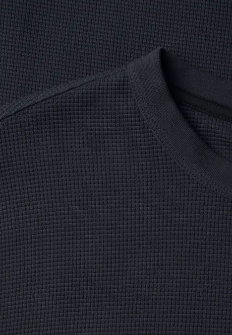 Nahaufnahme eines schwarzen Rundhals-Shirts mit Waffelstrickstruktur.