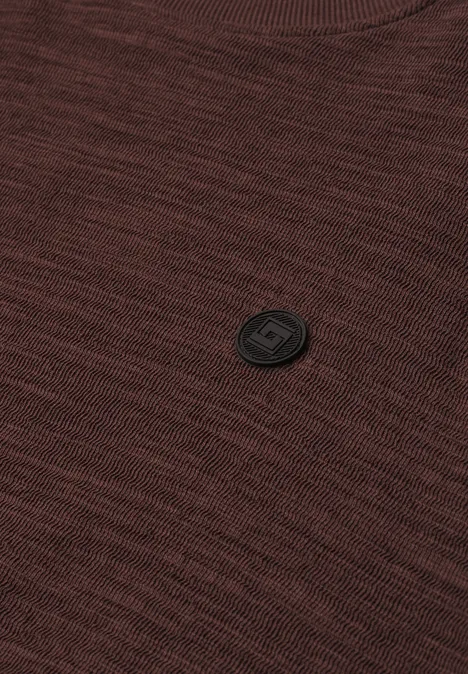 Langarm Shirt mit Rundhals in Unifarbe maroon brown Nahaufnahme eines braunen Strickpullovers mit schwarzem, rundem Logo-Badge