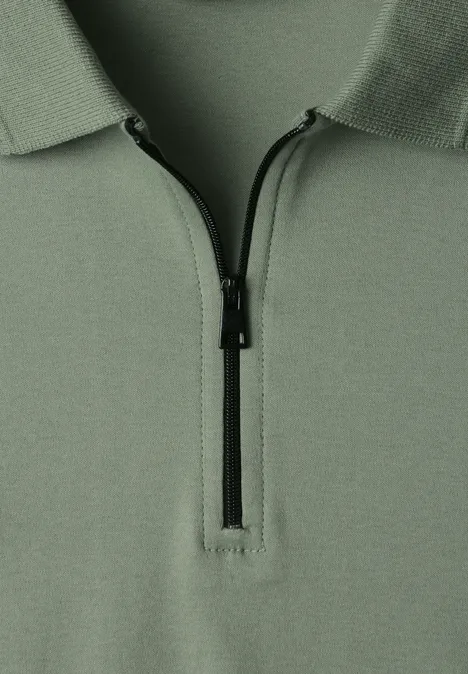 Nahe Ansicht eines hellgrünen Poloshirts mit kurzem, schwarzem Reißverschluss am Kragen