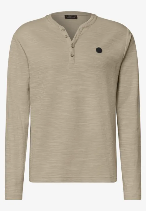 T-shirt henley à manches longues beige avec patte de boutonnage au col et petit patch logo sur la poitrine.