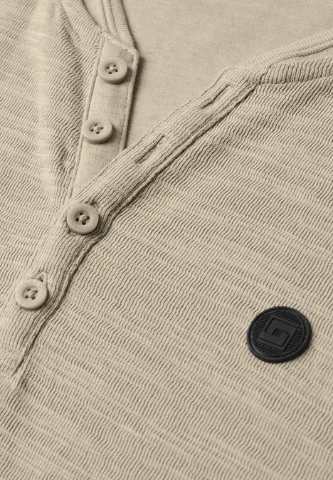 Henley beige en maille fine, patte de boutonnage et écusson rond sur la poitrine.