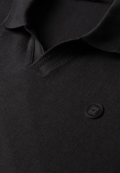 Polo noir avec col en V et petit écusson rond de logo sobre sur la poitrine.