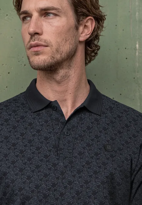 Langarm Poloshirt in Grafikprint dark ink blue Ein nachdenklich wirkender Mann mit kurzen braunen Haaren trägt ein dunkles Poloshirt und blickt seitlich.