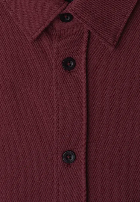 Nahaufnahme eines dunkelroten Hemds mit Knopfleiste und Kragen.