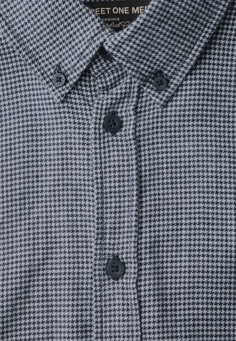 Gros plan sur une chemise à motif pied-de-poule fin gris, avec patte de boutonnage et col boutonné.