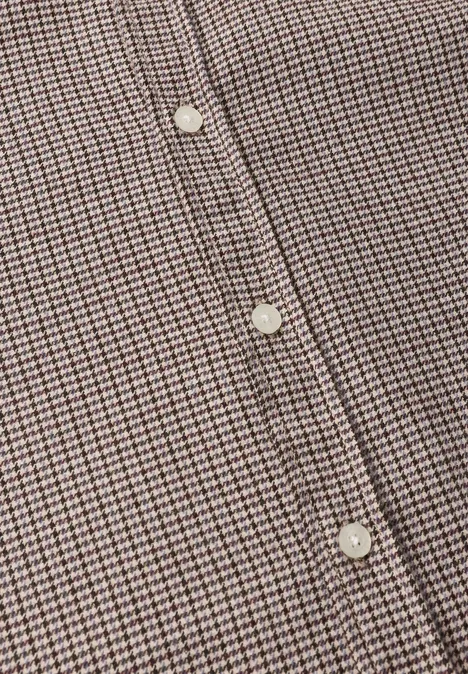 Gros plan d’une chemise à petits carreaux marron et blanc avec des boutons blancs.