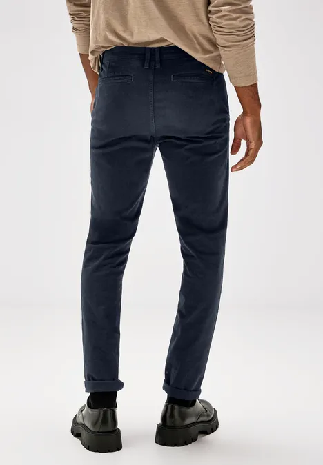 Mann in dunkelblauer Hose und beigen Pullover, Rückenansicht.