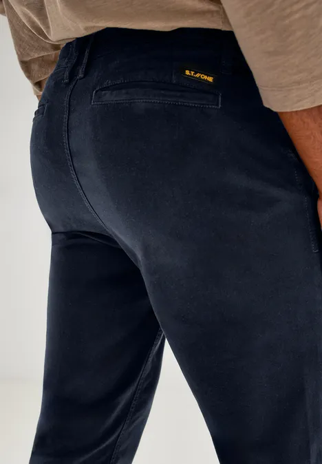 Nahaufnahme einer dunkelblauen Hose von hinten, Person trägt ein beiges Oberteil.