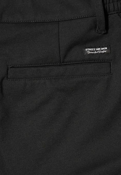 Gros plan d'un pantalon noir avec une poche arrière encastrée et une petite étiquette blanche au-dessus.