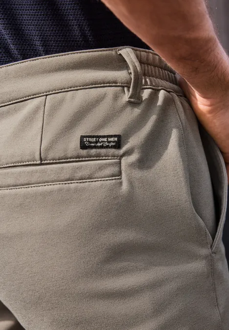 Nahaufnahme einer Person trägt khakifarbene Hose mit Gesäßtasche und Label am Bund.