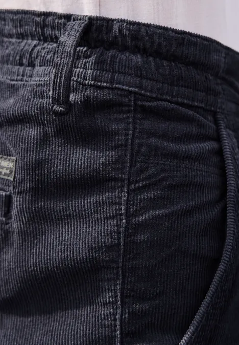 Nahaufnahme einer schwarzen Cordhose mit elastischem Bund und Gürtelschlaufen.