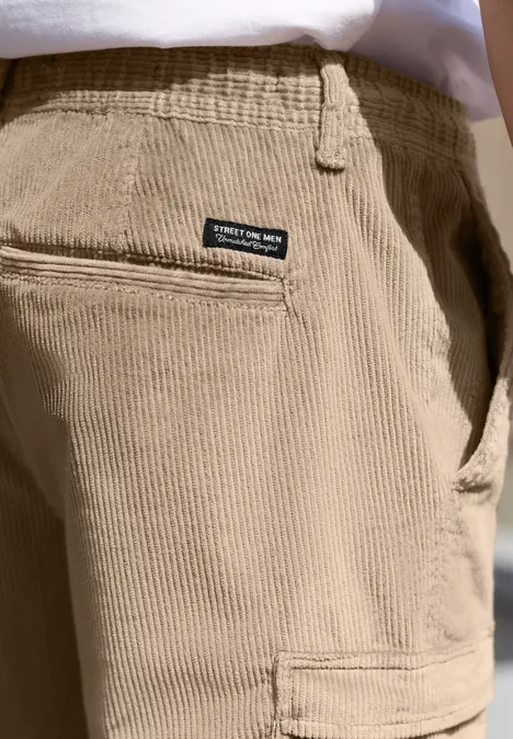 Nahaufnahme einer hellbeigen Cordhose mit Gesäßtasche und kleinem schwarzen Label.