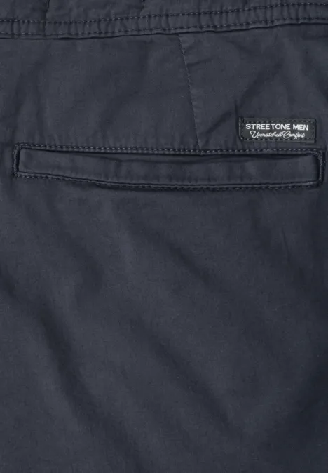 Nahaufnahme einer dunkelblauen Hose mit Gesäßtasche und kleinem Label 'STREET-TECH MEN Performance Wear'.