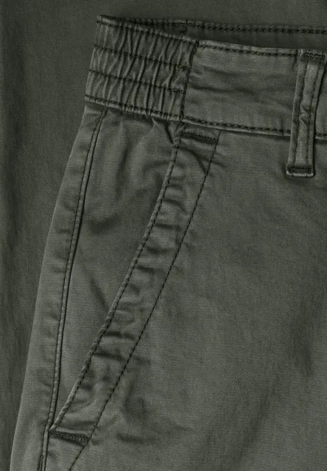 Nahaufnahme einer dunkelgrünen Hose mit elastischem Bund, Gürtelschlaufen und seitlicher Eingrifftasche.