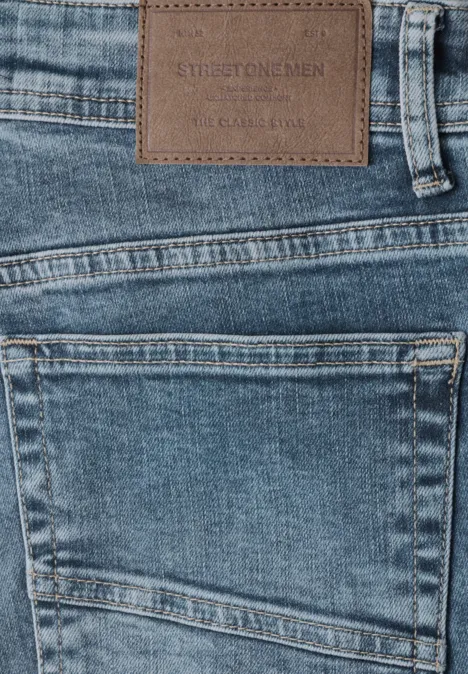 Slim Leg-jeans met Regular Fit soft greencast random wash Close-up van een blauwe spijkerbroek met leren label in de tailleband en een achterzak.
