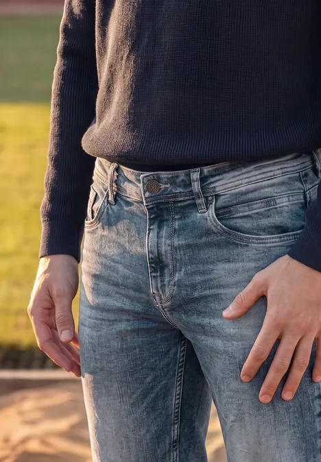 Straight Leg Jeans im Regular Fit soft greencast random wash Eine Person trägt draußen blaue Jeans und einen dunklen Pullover und steht auf sandigem Untergrund.