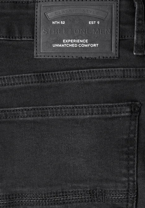Schwarze Jeansrückansicht mit aufgesetzter Gesäßtasche und Lederpatch 'Experience Unmatched Comfort'.