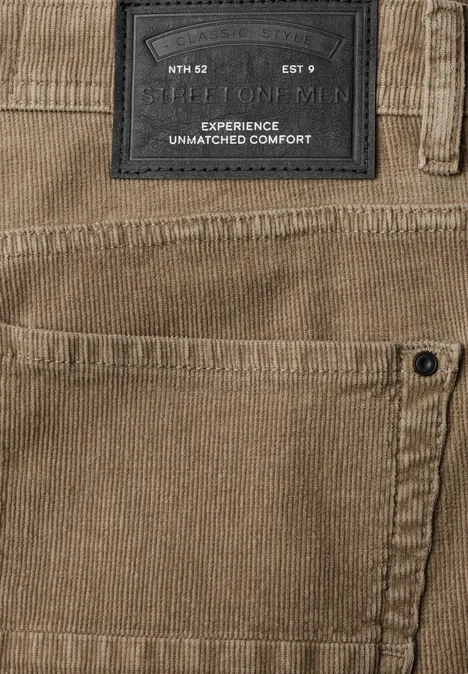 Nahansicht einer beigefarbenen Cordhose mit Label und seitlicher Tasche.
