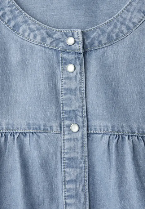 Hellblaue Denim-Bluse mit rundem Ausschnitt, Knopfleiste und Raffung unter der Brust.
