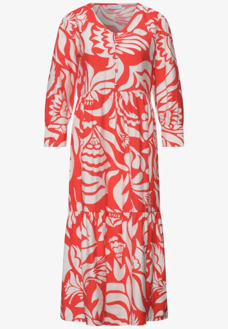 Koraalrode lange jurk met wit abstract patroon, lange mouwen, V-hals en geplooide rok