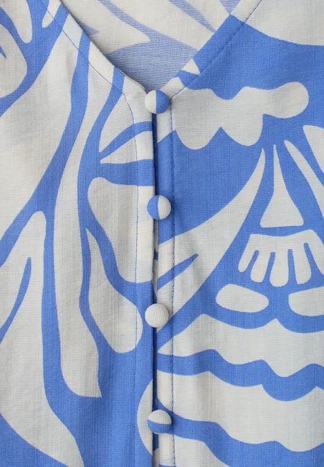 Nahaufnahme eines Kleiderstücks mit blau-weißem Muster und stoffbezogenen Knöpfen auf der Vorderseite.