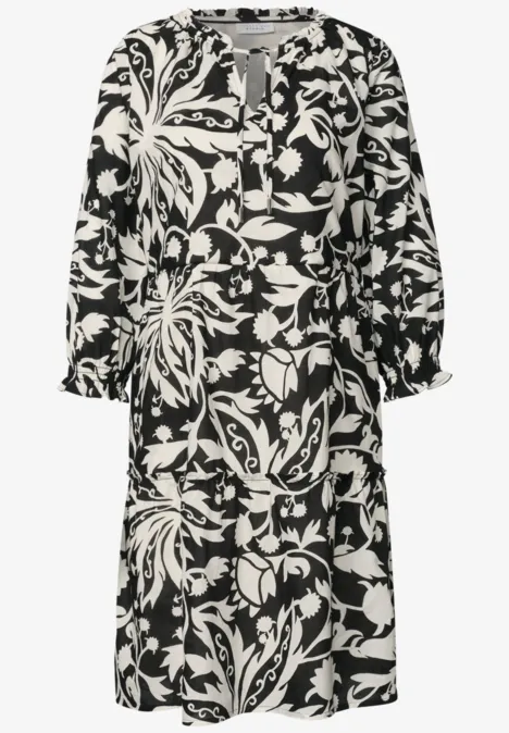 Schwarz-weißes Midikleid mit floralem Muster, langen Ärmeln und lockerem Schnitt.