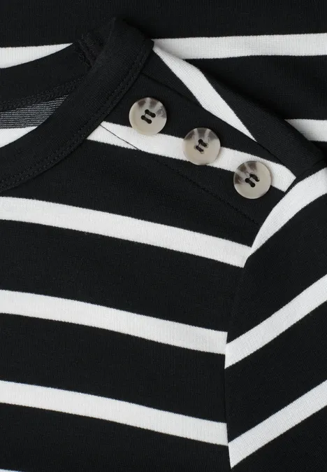Close-up van een zwart-wit gestreept bovenstuk met knoopsluiting op de schouder