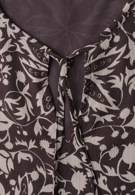 Close-up van een top met bloemmotieven en een strik bij de hals