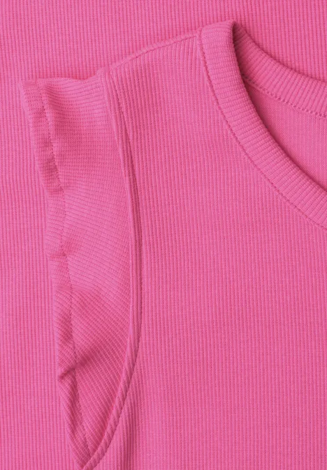 Close-up van een mouwloze roze ribgebreide top met ruches op de schouders.