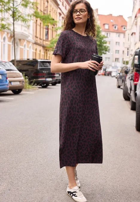Midkleid mit Rundhals und Leo-Muster very berry Frau in langem, dunklem Leokleid mit weißen Sneakern steht mit Handy in der Hand auf einer Straße.