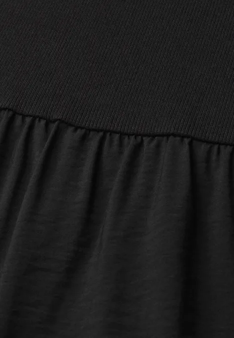 Gros plan sur un tissu noir, partie supérieure côtelée et bas froncé