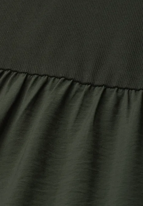 Vue en gros plan d’un vêtement vert olive avec couture, tissu côtelé en haut et lisse en bas