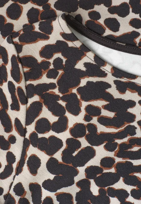 Nahaufnahme eines Kleidungsstücks mit braun-schwarzen Leopardenmuster auf beigem Stoff