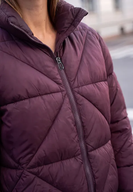 Close-up van persoon met een donkerpaars doorgestikte winterjas met ritssluiting.
