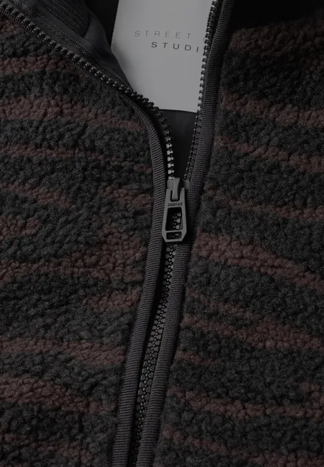 Gros plan d'une veste polaire brun-noir à motif, avec fermeture éclair et étiquette intérieure.