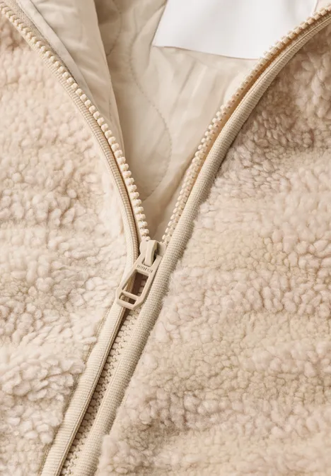 Gros plan d'une veste en polaire beige à zip avec intérieur duveteux apparent
