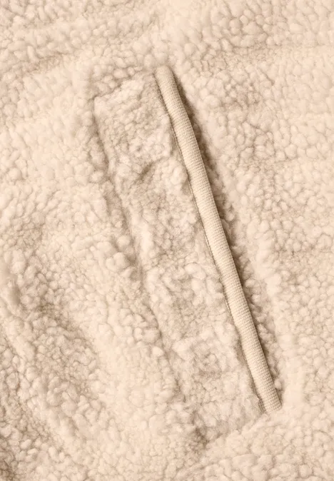 Gros plan d’un tissu polaire d’agneau beige avec couture et poche zippée
