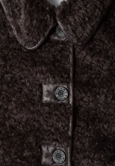 Zbliżenie brązowego płaszcza teddy z puchatą fakturą i widocznymi guzikami.