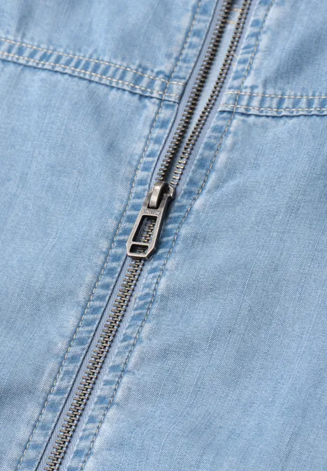 Close-up van een gesloten metalen ritssluiting op lichtblauw denim.