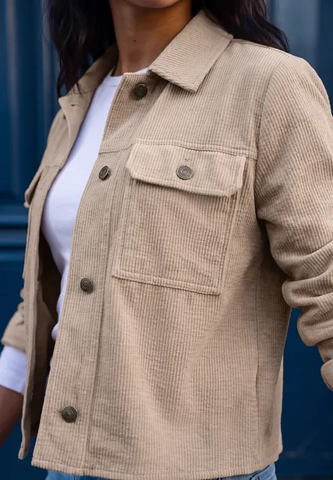 Eine Frau trägt eine hellbeige Cordjacke mit Brusttasche über weißem Shirt.