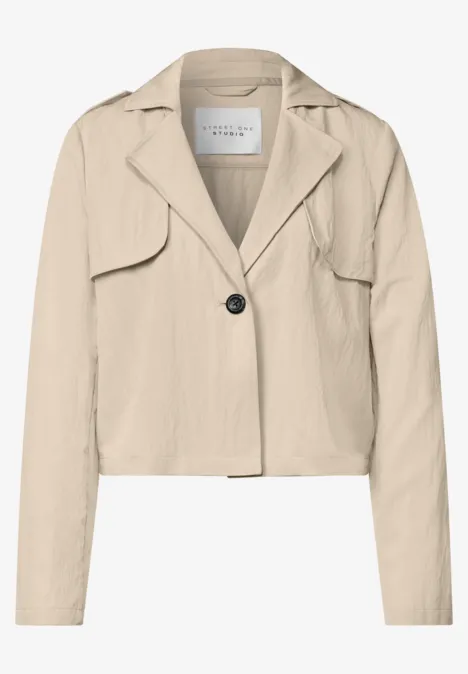Een kort gesneden, beige blazer met reverskraag, een knoopsluiting en lange mouwen.