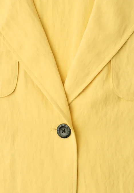 Gelbes Blazer-Sakko mit Revers und schwarzem Knopf in Nahaufnahme.