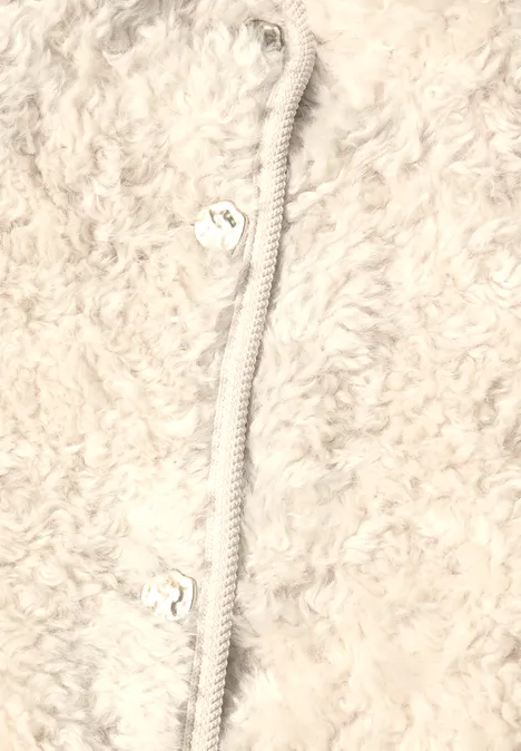 Nahaufnahme einer flauschigen weißen Fleecejacke mit Reißverschluss und herzförmigen Zugstoppern.