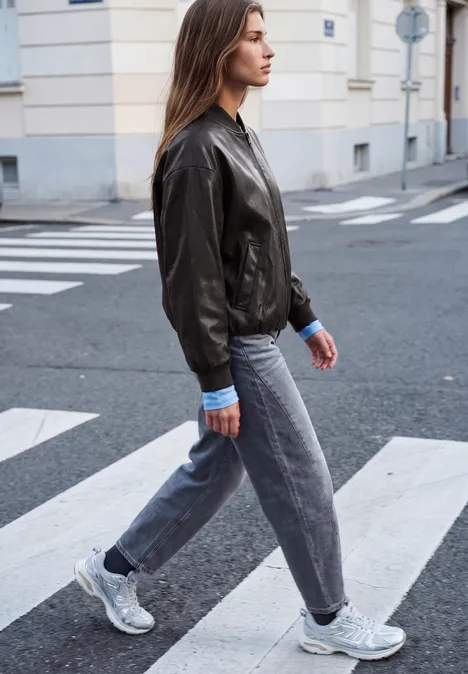 Blouson aspect cuir charred brown Junge Frau in Lederjacke, Jeans und Sneakers läuft über einen Zebrastreifen in der Stadt.