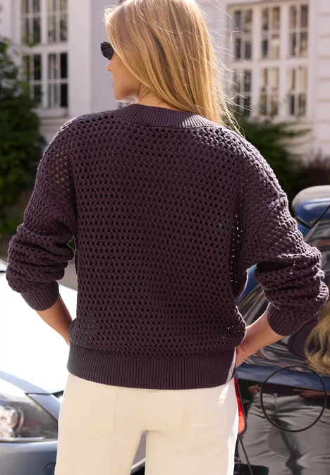 Cardigan mit Rundhals und Zipper very berry Blonde Frau von hinten in dunkelviolettem Strickpullover und weißen Hosen neben Autos.