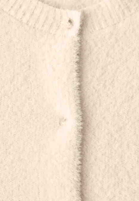 Nahaufnahme eines cremeweißen, flauschigen Cardigans mit Rundhalsausschnitt und Knopfleiste.