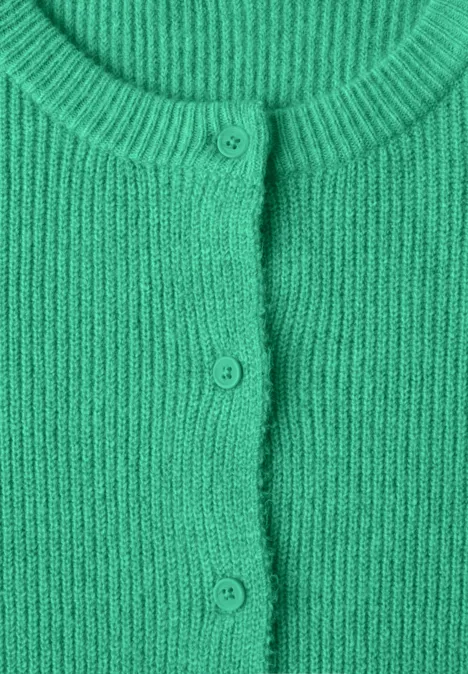 Nahaufnahme eines grünen Strickcardigans mit Rundhalsausschnitt und drei Knöpfen.